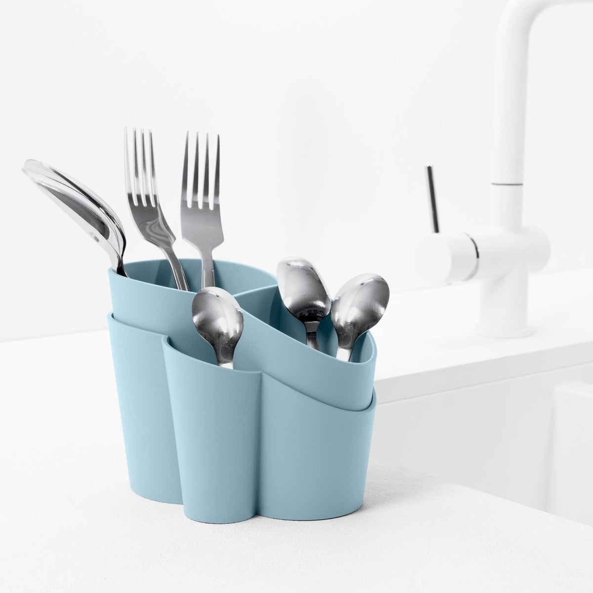 Blim+ Gocciolo Cutlery Drainer in blue, holding cutlery beside a tap