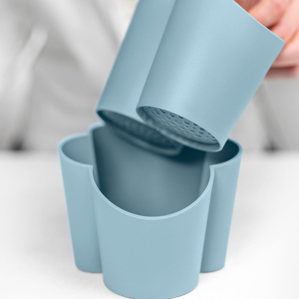 Blim+ Gocciolo Cutlery Drainer in blue, with the top part being lifted by hand
