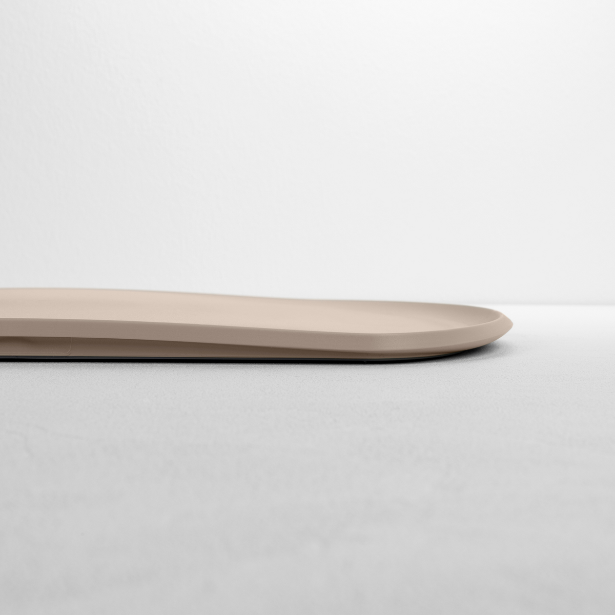 Blim+ Skateboard Chopping Board Medium in taupe, side view showing the thin profile