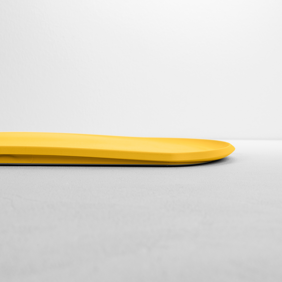 Blim+ Skateboard Chopping Board Medium in yellow, side view showing the thin profile