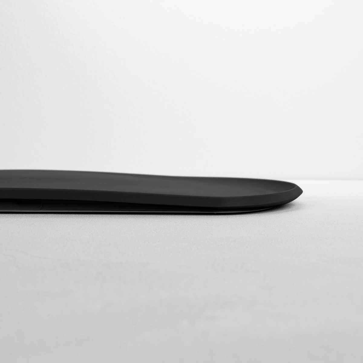 Blim+ Skateboard Chopping Board Medium in black, side view showing the thin profile