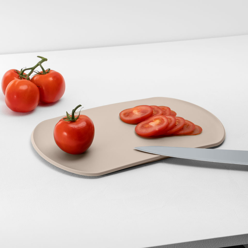 Blim+ Skateboard Chopping Board Medium in taupe, with sliced tomatoes and a knife