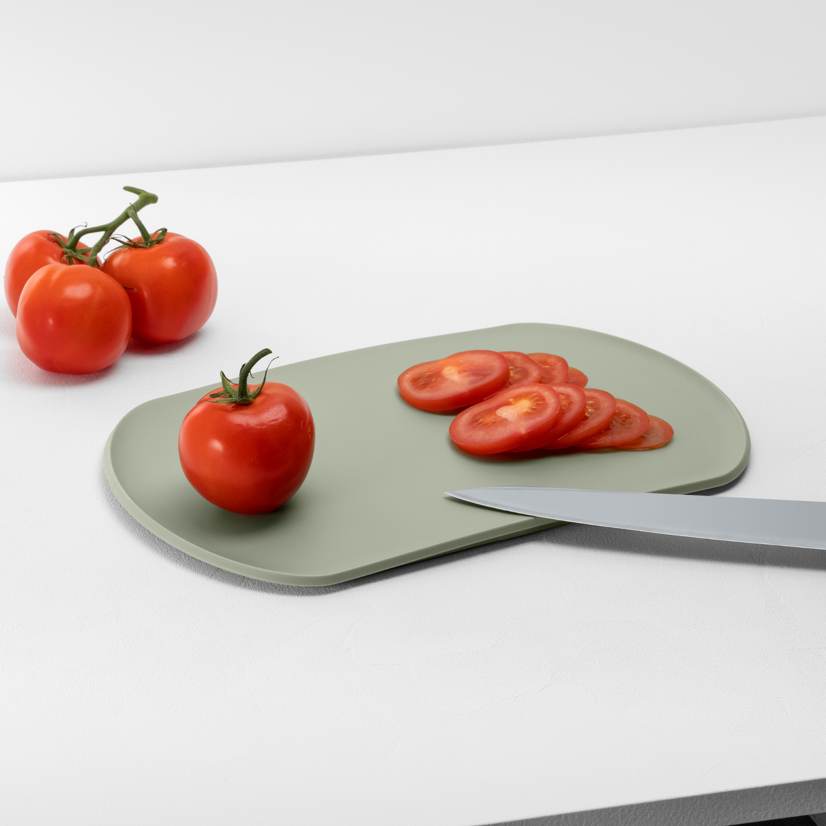 Blim+ Skateboard Chopping Board Medium in green, with sliced tomatoes and a knife
