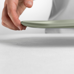 Blim+ Skateboard Chopping Board Medium in green, lifted by hand to show its thin profile