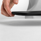 Blim+ Skateboard Chopping Board Medium in black, lifted by hand to show its thin profile