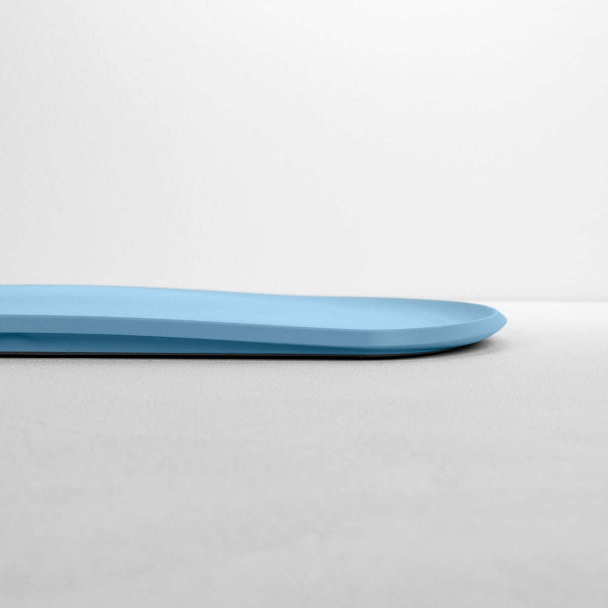 Blim+ Skateboard Chopping Board Medium in blue, side view showing the thin profile