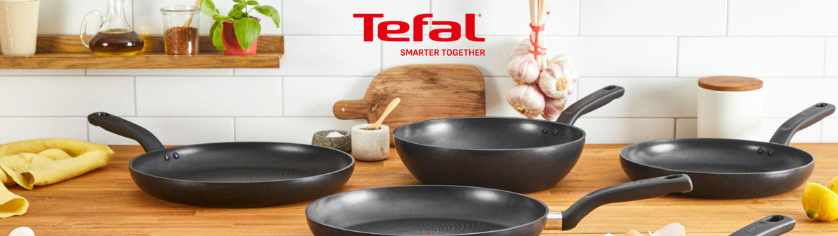 Tefal non-stick frying pans and a wok on a kitchen counter