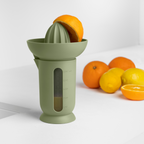 Blim+ UFO Juicer with QB Carafe in green, beside fresh oranges