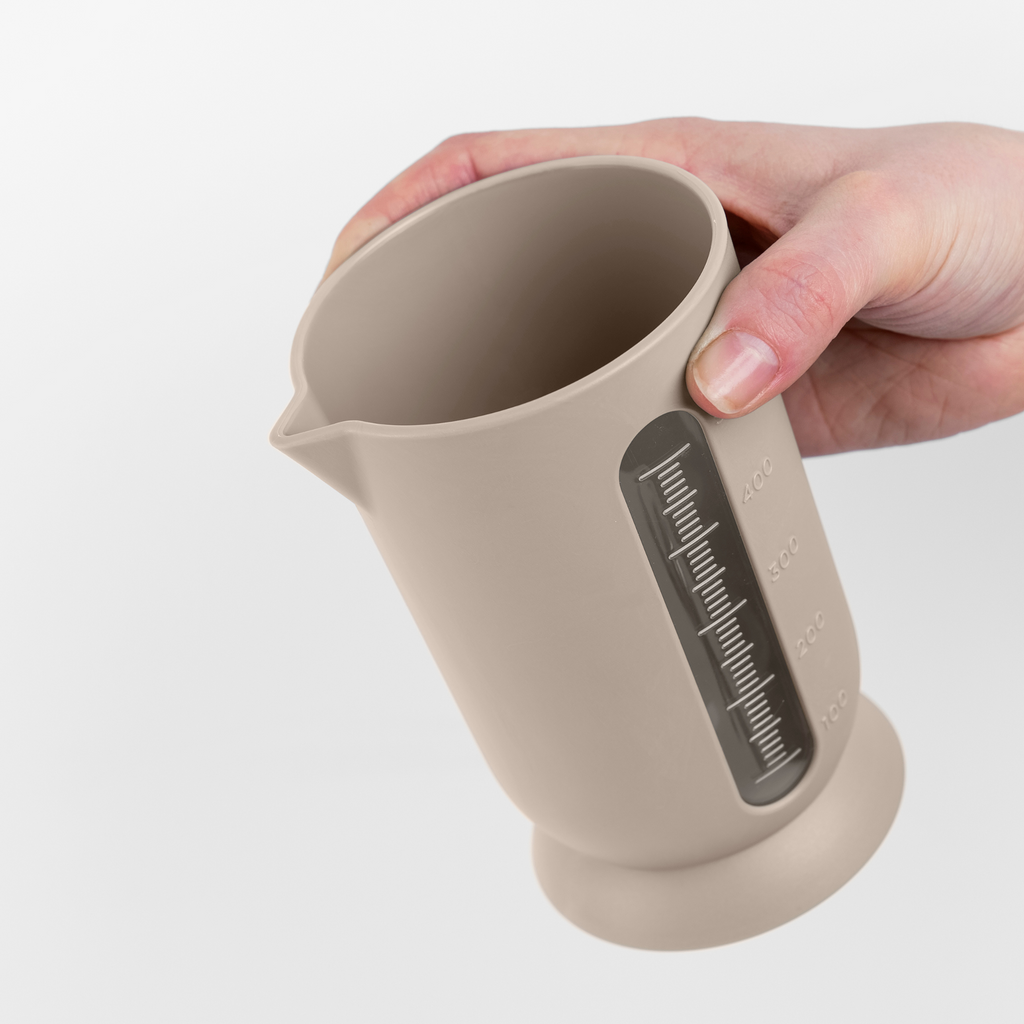 Blim+ UFO Juicer with QB Carafe in taupe, carafe held in a hand